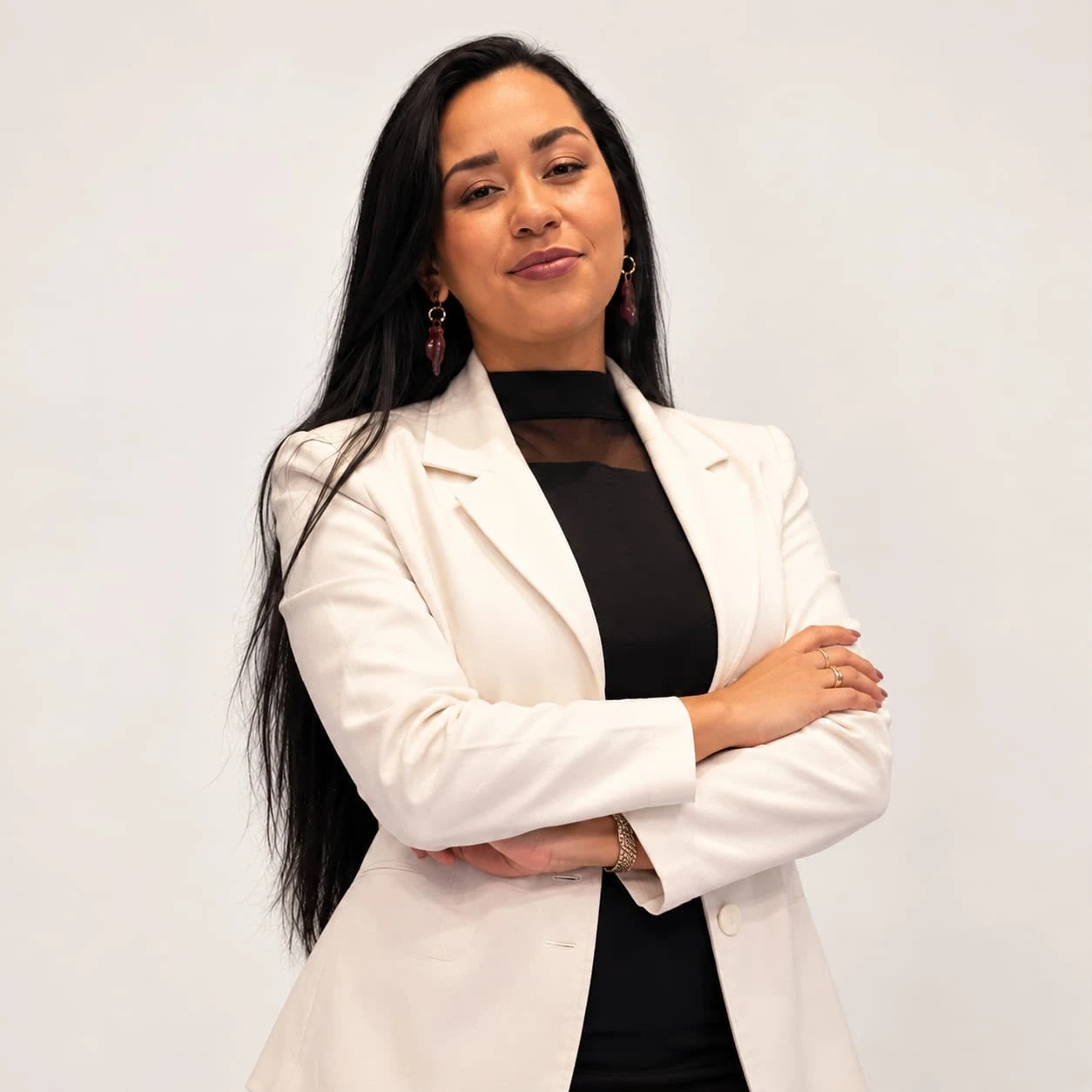Nathália Nunes de blazer branco e braços cruzados