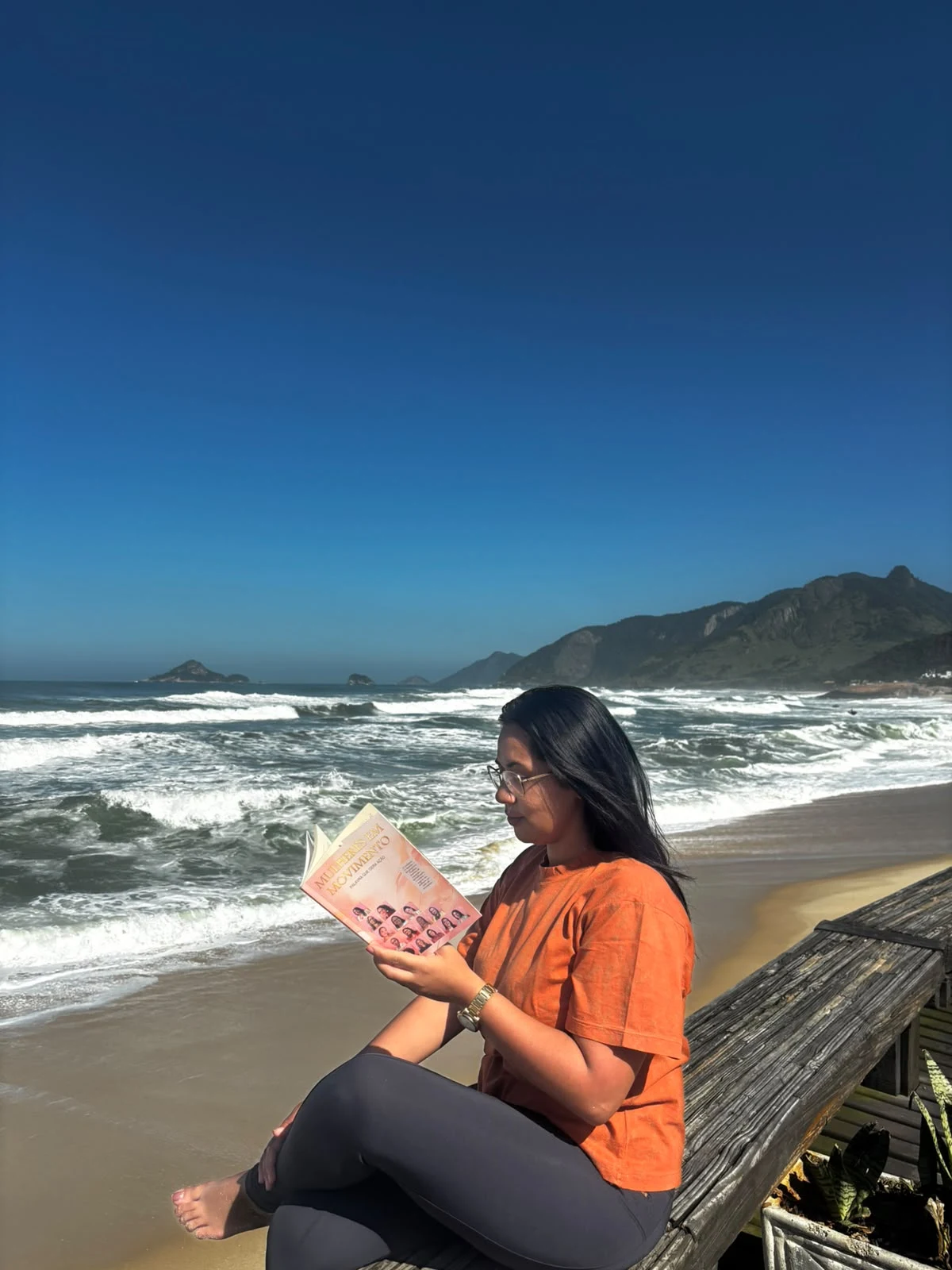 Nathália Nunes com um livro à beira-mar